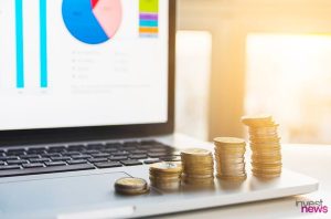 Laptop com gráficos financeiros e pilhas de moedas crescendo, simbolizando investimento e crescimento. (88 caracteres)