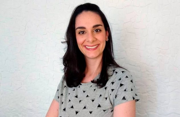 Mulher sorrindo com cabelo escuro e camisa estampada contra fundo branco.