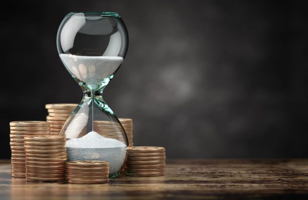 Ampulheta tendo ao fundo moedas