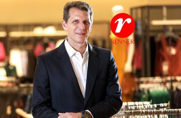 Homem de terno sorrindo em loja de roupas. Logotipo Renner no canto superior direito.