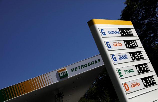 Posto Petrobras com placa de preços de combustíveis (gasolina, etanol, diesel) sob céu azul.