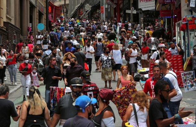 Pessoas caminham em rua de comércio popular em São Paulo