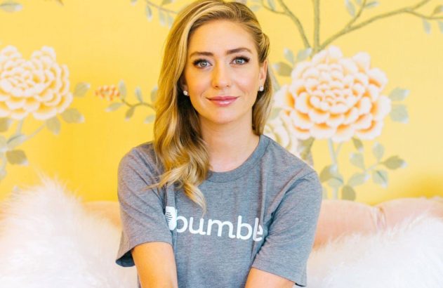 Mulher de camiseta Bumble sentada, sorrindo para a câmera. Fundo amarelo com estampa floral e ramos.