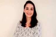 Mulher de cabelos escuros e blusa estampada sorri para a câmera.