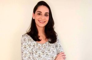 Mulher sorrindo com blusa estampada e braços cruzados.