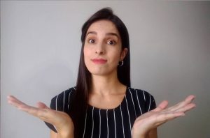 Mulher com olhos arregalados e mãos abertas, em gesto de dúvida.