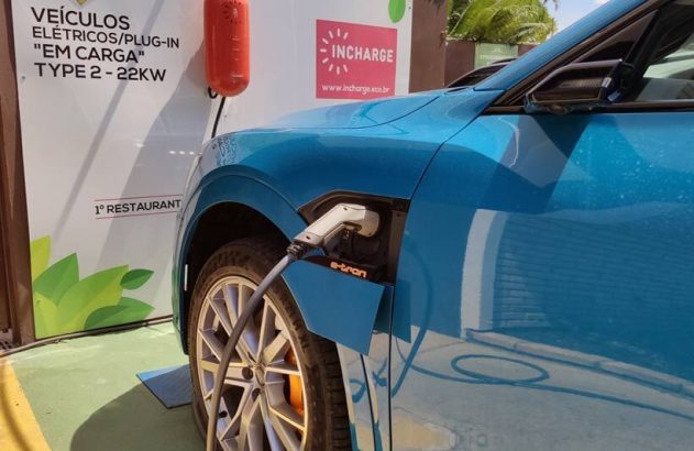 Carro elétrico azul carregando em estação Incharge. Placa informa "VEÍCULOS ELÉTRICOS EM CARGA, TYPE 2 - 22KW".