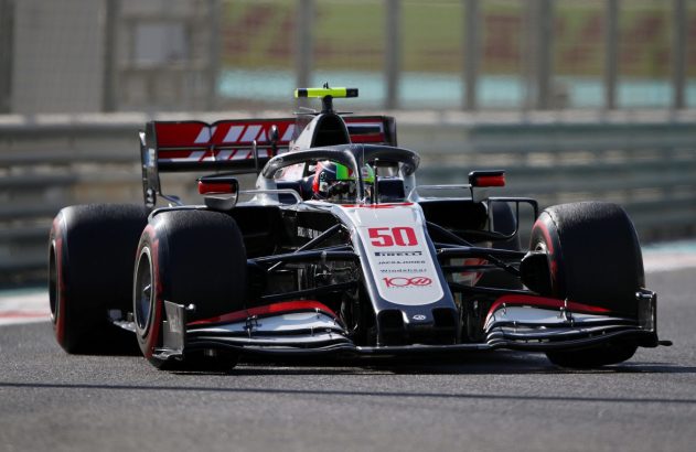 Carro de corrida F1 nº 50 preto, branco e vermelho acelerando na pista.