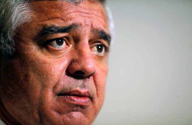 Close-up do rosto de um homem com cabelo grisalho e expressão pensativa, olhando para o lado direito.
