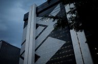 Prédio moderno de vidro e concreto do Banco do Brasil ao entardecer, com logo estilizado e luzes acesas.