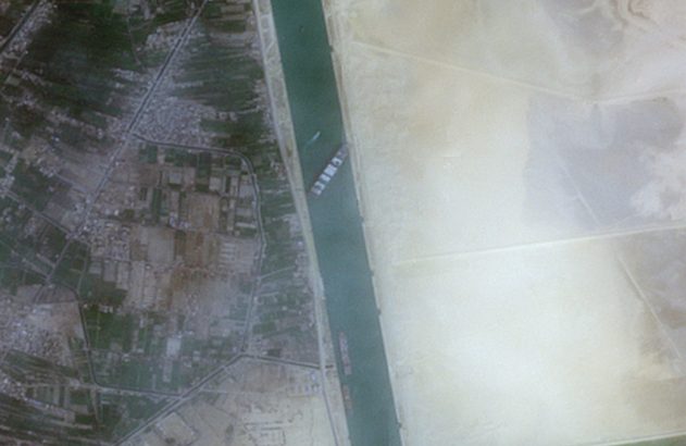 Vista aérea do Canal de Suez dividindo área cultivada e deserto, com navios.
