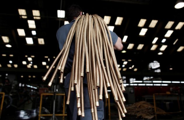 Operários carregam fios de cobre no ombro