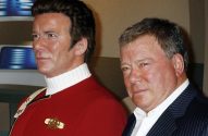 William Shatner ao lado de uma estátua de cera do Capitão Kirk em uniforme vermelho de Star Trek.