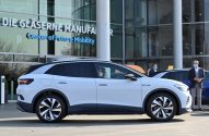 SUV elétrico branco VW ID.4 em frente ao "Center of Future Mobility". Pessoas com máscaras observam o carro.