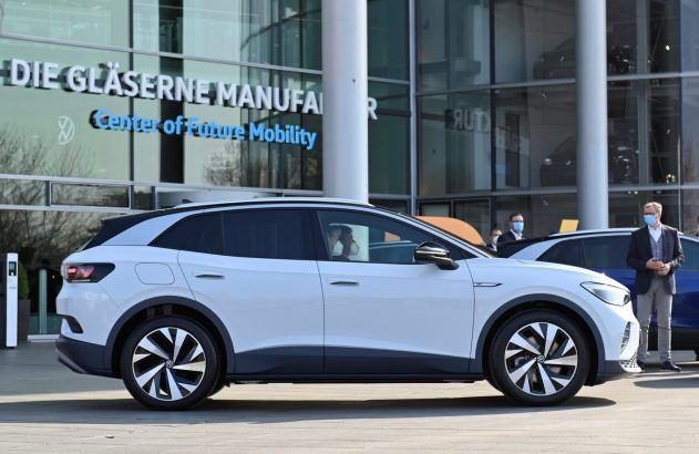 SUV elétrico branco VW ID.4 em frente ao "Center of Future Mobility". Pessoas com máscaras observam o carro.