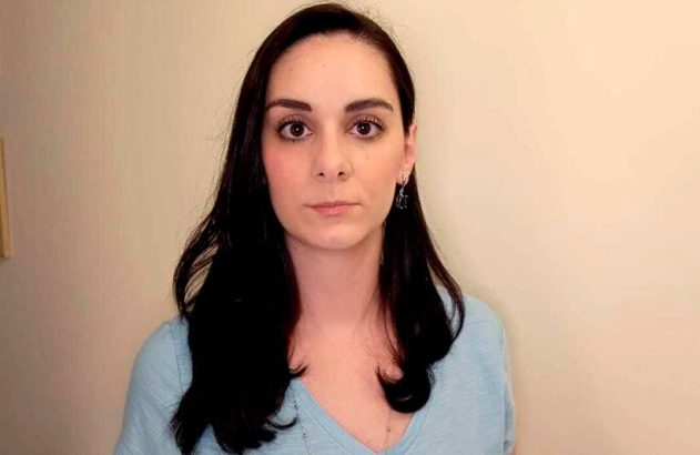 Retrato de mulher com cabelos escuros e olhar intenso, vestindo blusa azul.