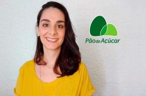 Mulher sorrindo para a câmera, com blusa amarela. Ao lado, o logo Pão de Açúcar.