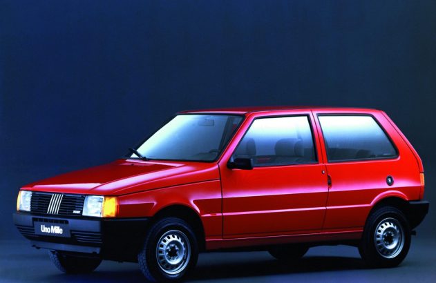 Fiat Uno Mille vermelho de 2 portas estacionado. Fundo azul escuro.
