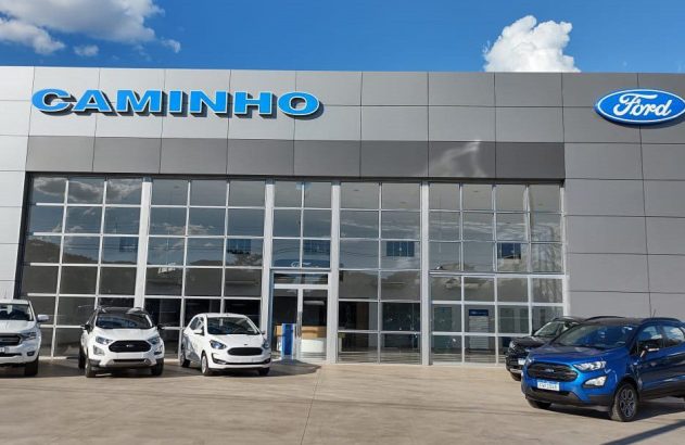 Concessionária Ford Caminho: edifício moderno com fachada de vidro e diversos veículos expostos à frente.