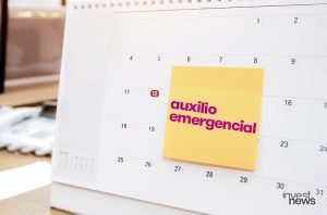 Calendário com post-it amarelo 'auxílio emergencial' e data circulada.