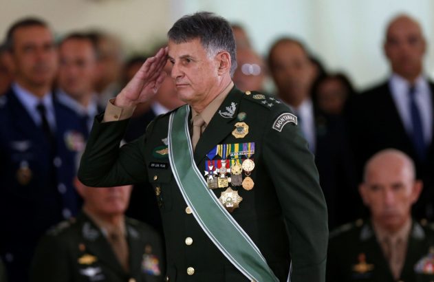 Militar fardado de verde escuro, com medalhas e faixa, prestando continência.