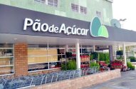 Entrada do supermercado Pão de Açúcar, com carrinhos de compra e plantas e flores à venda.