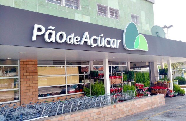 Entrada do supermercado Pão de Açúcar, com carrinhos de compra e plantas e flores à venda.