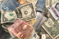 Pilha de diversas notas e moedas de diferentes países, como dólar, euro e yuan.