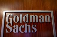 Placa de Goldman Sachs com letras cinzas elevadas e moldura em fundo de madeira.