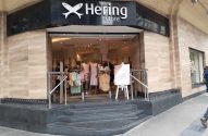 Fachada da Hering store. Logo de peixe, entrada com degraus, interior com roupas e manequins e cavalete na frente.