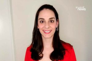 Mulher sorrindo com cabelo escuro e blusa vermelha, olhando para a câmera.