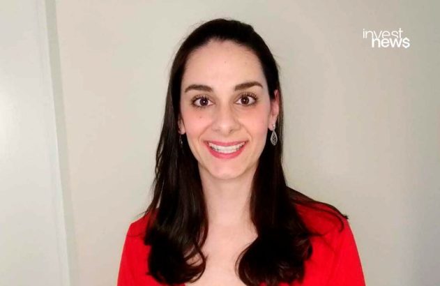 Mulher sorrindo com cabelo escuro e blusa vermelha, olhando para a câmera.