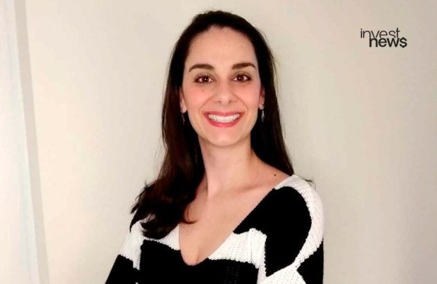 Retrato de mulher sorrindo, com suéter preto e branco. Logo "invest news" no canto superior direito.