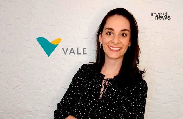 Mulher sorridente em frente a parede branca com logos da VALE e investnews.