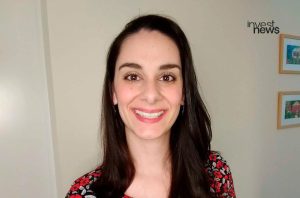 Mulher sorridente olhando para a câmera. Logo Investnews no canto superior.