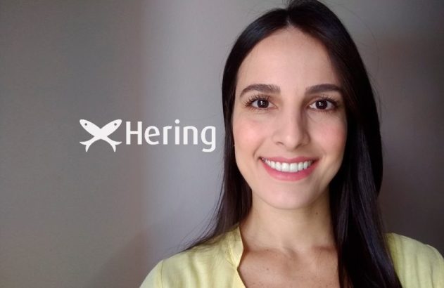 Mulher sorridente com o logo da Hering (dois peixes) ao fundo.