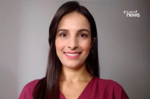Retrato de mulher com cabelo escuro sorrindo. Fundo cinza com logo 'invest news'.