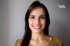 Retrato de mulher sorrindo, com cabelo escuro e blusa dourada. Logo "invest news" no canto superior direito.