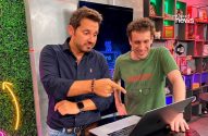 Dois homens interagem com um laptop. Um aponta para a tela, o outro sorri.
