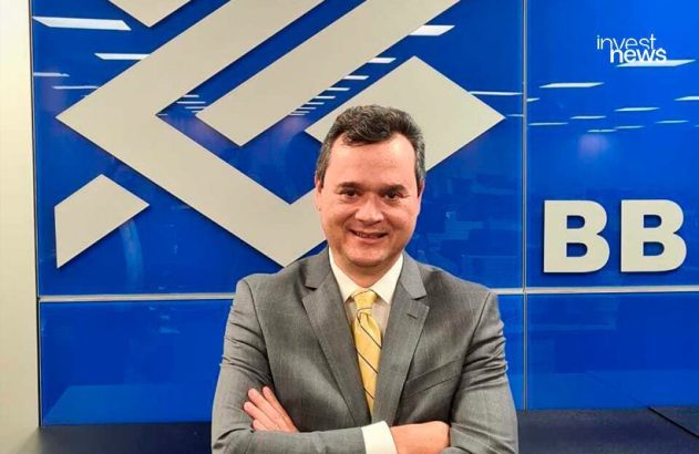 Homem sorridente de terno e gravata amarela, braços cruzados, em frente a logotipo do BB e investnews.