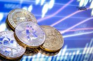 Moedas físicas de criptomoedas (Bitcoin, etc.) em superfície refletiva. Fundo azul com gráficos de mercado. invest news.