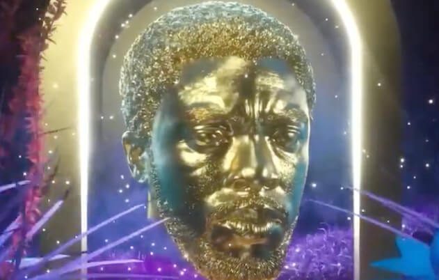 Busto dourado de um homem emoldurado por arcos luminosos, com partículas cintilantes e folhagens roxas/azuis.