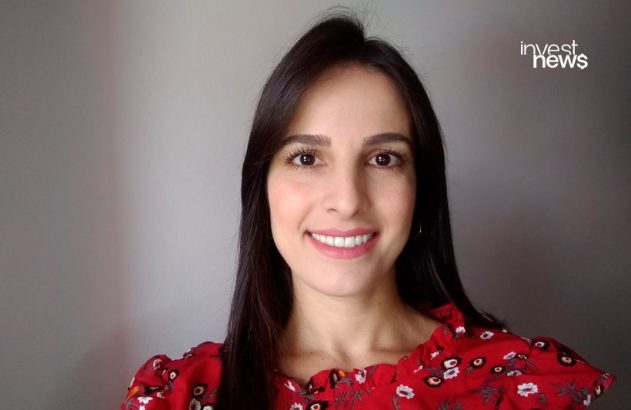 Mulher de cabelo escuro sorrindo, vestindo blusa vermelha floral. No canto superior direito, o logo "invest news".