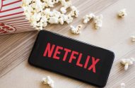 Pipoca derrubada ao lado de um celular com a logo da Netflix na tela, ilustrando o tema: história da netflix