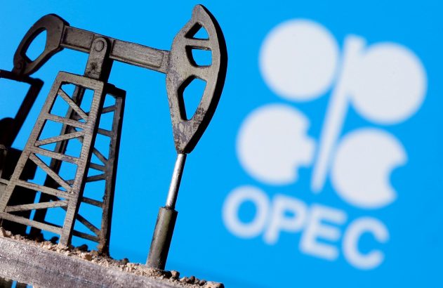 Miniatura de bomba de petróleo com logotipo desfocado da OPEP em fundo azul.