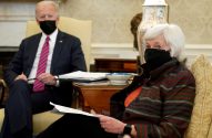 Joe Biden e Janet Yellen, ambos de máscara, sentados em reunião, Yellen em primeiro plano com papéis.