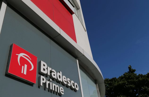Fachada de prédio Bradesco Prime com letreiro vermelho e branco, janelas escuras e céu azul.