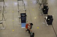 Passageiro com bagagem na área de check-in da Azul, com marcas de distanciamento no chão do aeroporto.