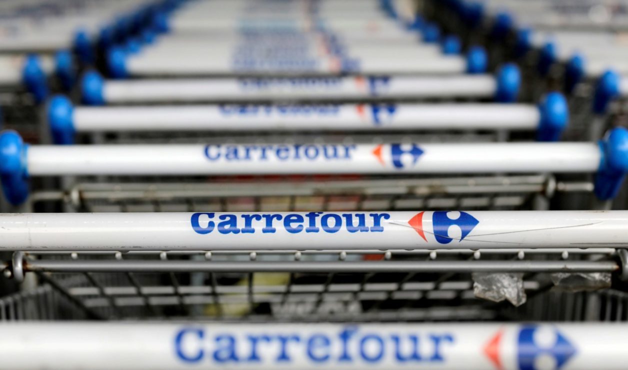 Cabos de carrinhos de compras Carrefour com nome e logo, alinhados em fileira.