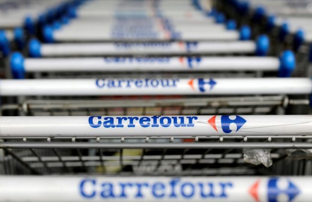 Cabos de carrinhos de compras Carrefour com nome e logo, alinhados em fileira.